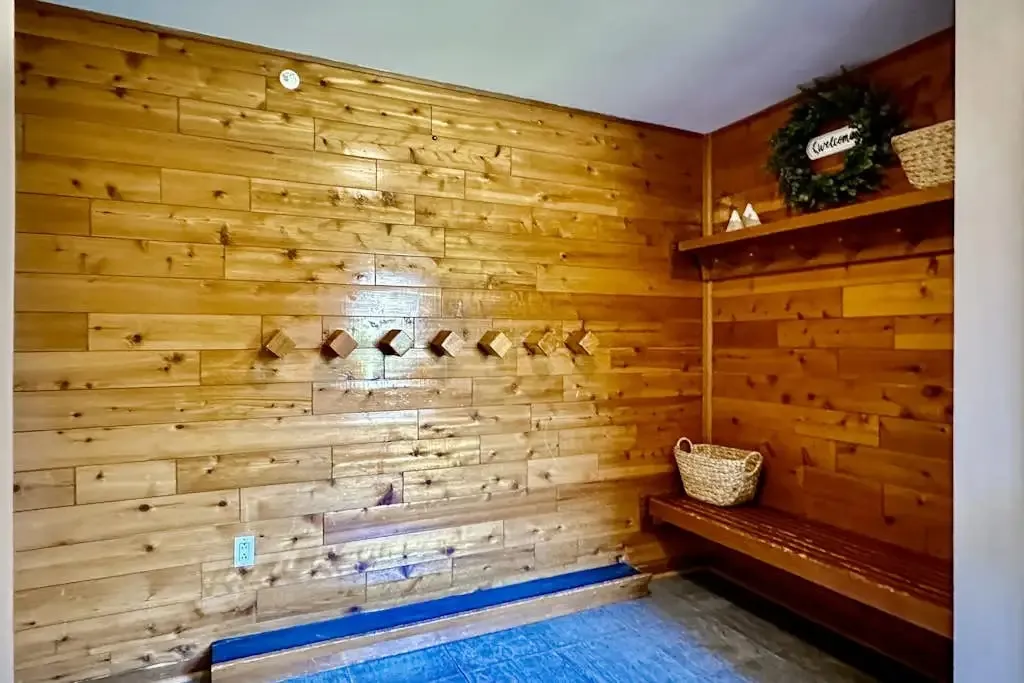 Wood-paneled mudroom with coat hooks, a bench, and woven storage baskets