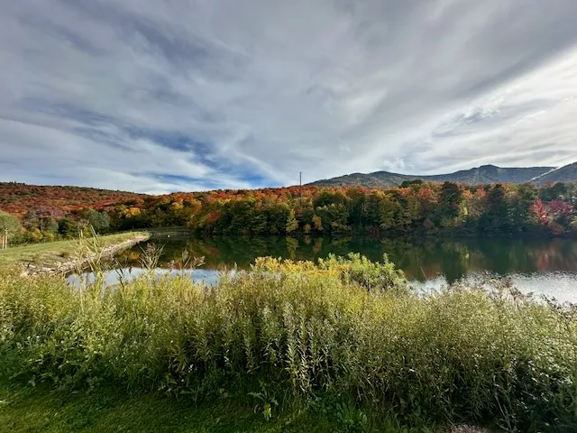 Red and orange foliage reflected in a pond below a Killington mountainside