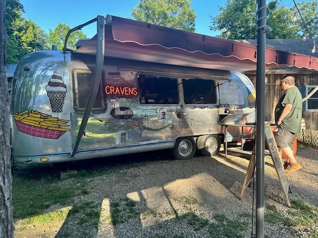 Silver Airstream food trailer with a neon CRAVENS sign and ice cream and fries artwork