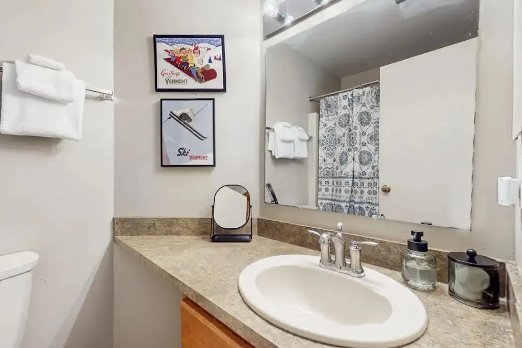 Ensuite bathroom toilet and towel rack with framed Vermont ski artwork